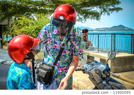 father and son wearing helmets are going to go on a motorbike in Koh Samui 11992095