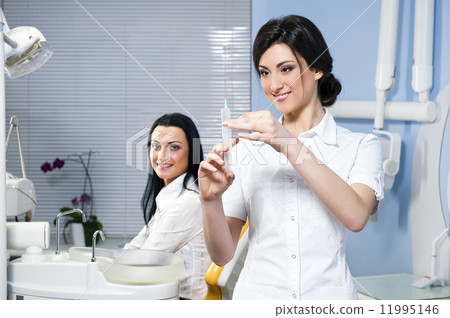 Attractive woman dentist with medical syringe and smiling patien Attractive woman dentist with medical syringe and smiling patien 11995146