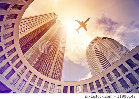 plane flying over modern office towers 11996142