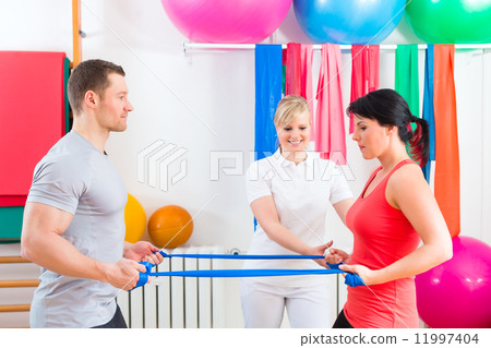 Physiotherapist giving patients gymnastic exercise 11997404