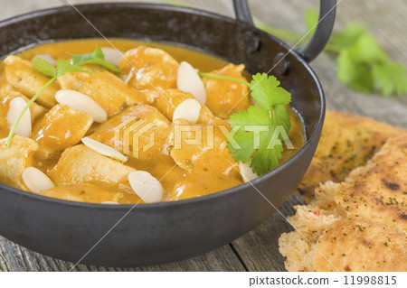 Chicken Korma - Chicken on a mildly spiced creamy sauce on a wooden background. Indian cuisine. 11998815