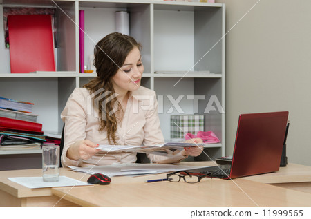 Business woman reading a magazine in the office 11999565