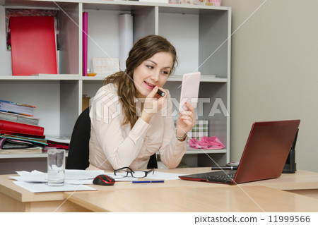 Business girl paints lips with lipstick in the office Business girl paints lips with lipstick in the office 11999566