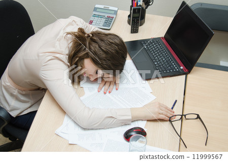 Tired woman asleep on a workplace at office Tired woman asleep on a workplace at office 11999567