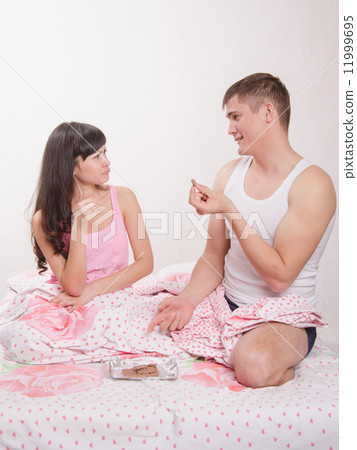Guy in bed teasing girl chocolate Guy in bed teasing girl chocolate 11999695