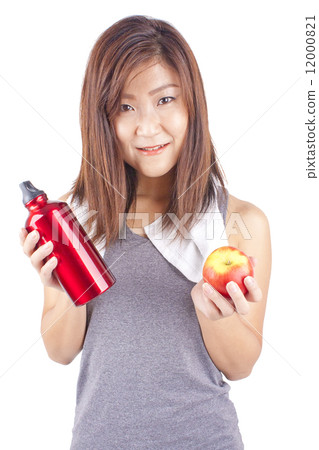 Young and fit pretty girl in exercise outfit holding red water bottle and red apple 12000821