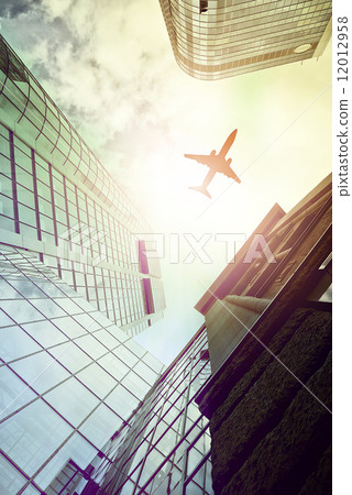 plane flying over modern office towers 12012958