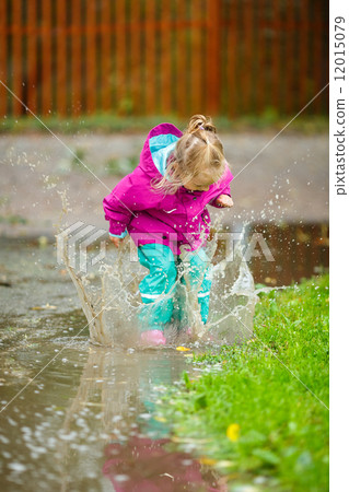 Happy little girl plays in a puddle 12015079