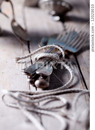 Vintage spoon and forks roped on a wooden table Vintage spoon and forks roped on a wooden table 12028010