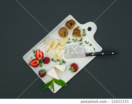 Cheese and fruit set on a dark surface 12031315