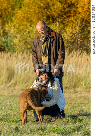 Couple playing with dog sunny autumn park Couple playing with dog sunny autumn park 12034084