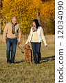 Couple walking dog in autumn sunny park 12034090