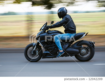 Young man riding a sport motorcycle on the road Young man riding a sport motorcycle on the road 12042209
