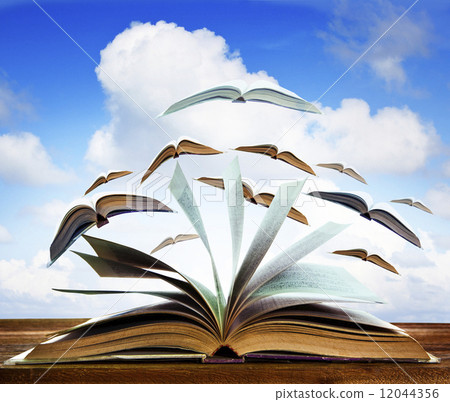 open old book page on wood table with flying book page against b 12044356