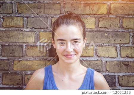 portrait of a smiling teenager girl leaning against a brick wall 12051233
