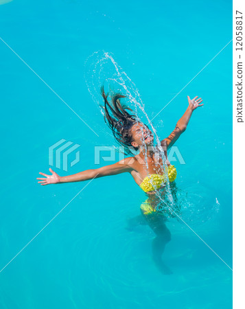 young tanned girl throwing wet hair back in swimming pool 12058817