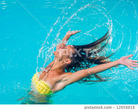 young tanned girl throwing wet hair back in swimming pool 12058818