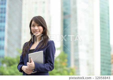 Successful young Chinese business woman with mobile device tablet iPad in front of office building Successful young Chinese business woman with mobile device tablet iPad in front of office building 12058843
