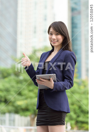 Successful young Chinese business woman with tablet iPad give thumbs up in front of office building Successful young Chinese business woman with tablet iPad give thumbs up in front of office building 12058845