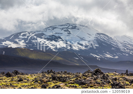 Icelandic volcano with snow and cloudy sky 12059019