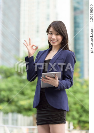 Successful young Chinese business woman with tablet iPad in front of office building giving OK sign Successful young Chinese business woman with tablet iPad in front of office building giving OK sign 12059069