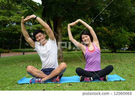 Asian make and female doing yoga in a park 12060068