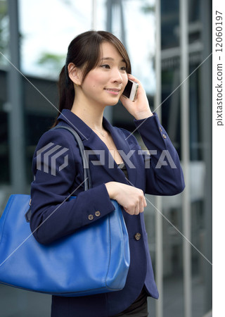 One young successful Chinese business woman using mobile phone in front of glass building 12060197