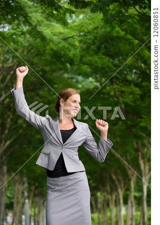 Victorious young successful caucasian business woman celebrating along of green walkway 12060851
