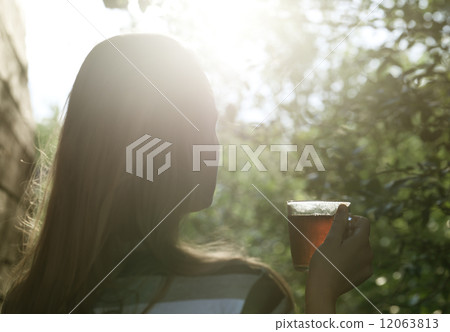 Woman with cup of tea in evening sunlight 12063813