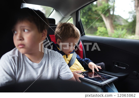 Two boys traveling on the back seat of a car Two boys traveling on the back seat of a car 12063862