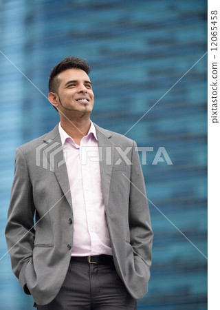 Portrait of one successful young Malay business man in suit standing in front of office buildings 12065458