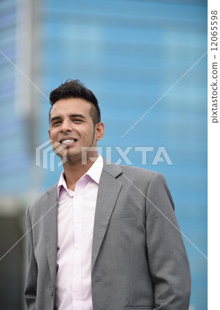 Portrait of one successful young Malay business man in suit standing in front of office building 12065598
