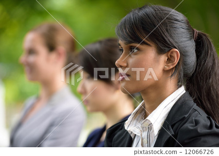 Team leader of 3 young successful mixed race business women standing along green walkway Team leader of 3 young successful mixed race business women standing along green walkway 12066726