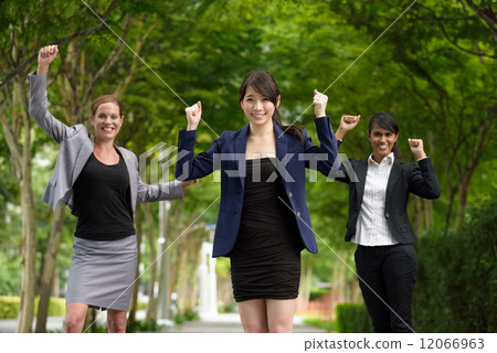 3 victorious young business women celebrating by punching their fist in the air along green walkway 3 victorious young business women celebrating by punching their fist in the air along green walkway 12066963