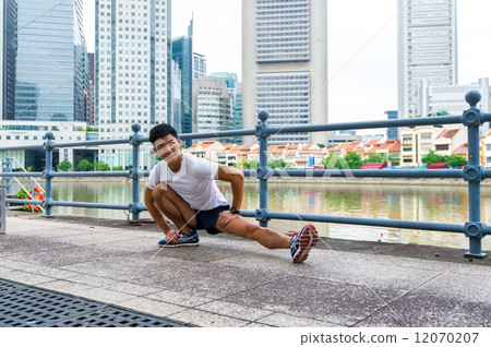 Young asian chinese man stretching / exercising outdoor in the city Young asian chinese man stretching / exercising outdoor in the city 12070207