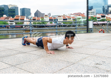 Young and healthy asian male stretching / exercising outdoor in the city 12070860