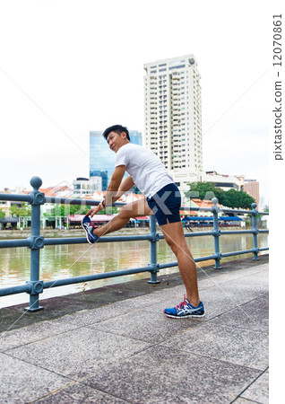 Young and healthy asian male stretching / exercising outdoor in the city 12070861