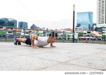 Young and healthy asian male stretching / exercising outdoor in the city 12070862