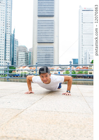 Young and healthy asian male stretching / exercising outdoor in the city 12070863