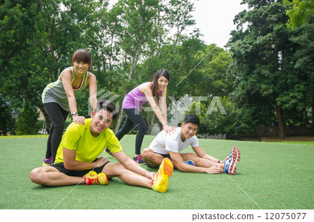 Two groups of young Asian couple helping each other to warm up before an execise in the outdoor park 12075077