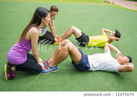 Two groups of young Asian couple helping each other to warm up before an execise in the outdoor park 12075079