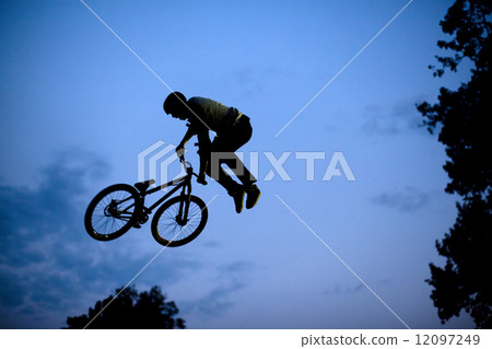 Silhouette of a man doing a jump with a bmx bike Silhouette of a man doing a jump with a bmx bike 12097249