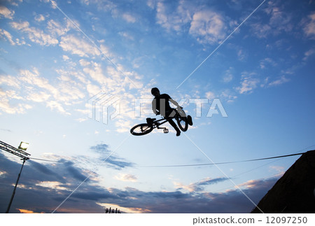 Silhouette of a man doing a jump with a bmx bike Silhouette of a man doing a jump with a bmx bike 12097250