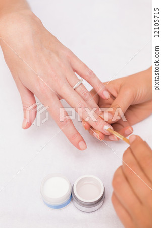 Nail technician giving customer a manicure 12105715