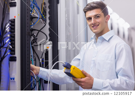 Technician smiling at camera while fixing server Technician smiling at camera while fixing server 12105917