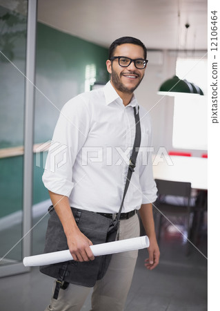 Casual architect smiling at camera holding blueprint 12106464