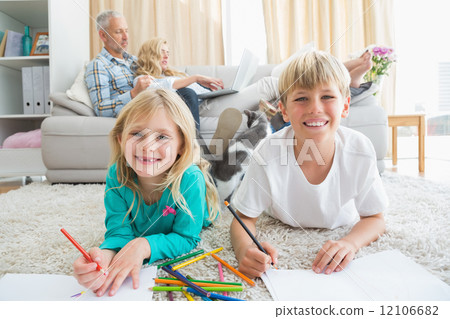 Siblings colouring and drawing on the floor 12106682