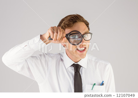 Geeky businessman looking through magnifying glass Geeky businessman looking through magnifying glass 12107049