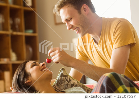 Young couple cuddling on the couch under blanket 12107557