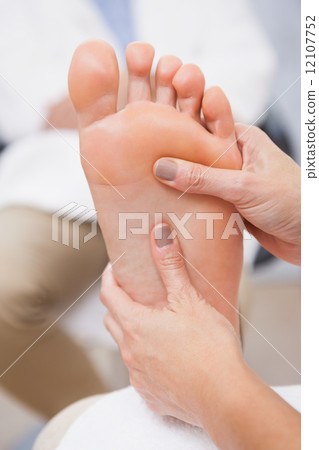 Pedicurist massaging customers foot 12107752